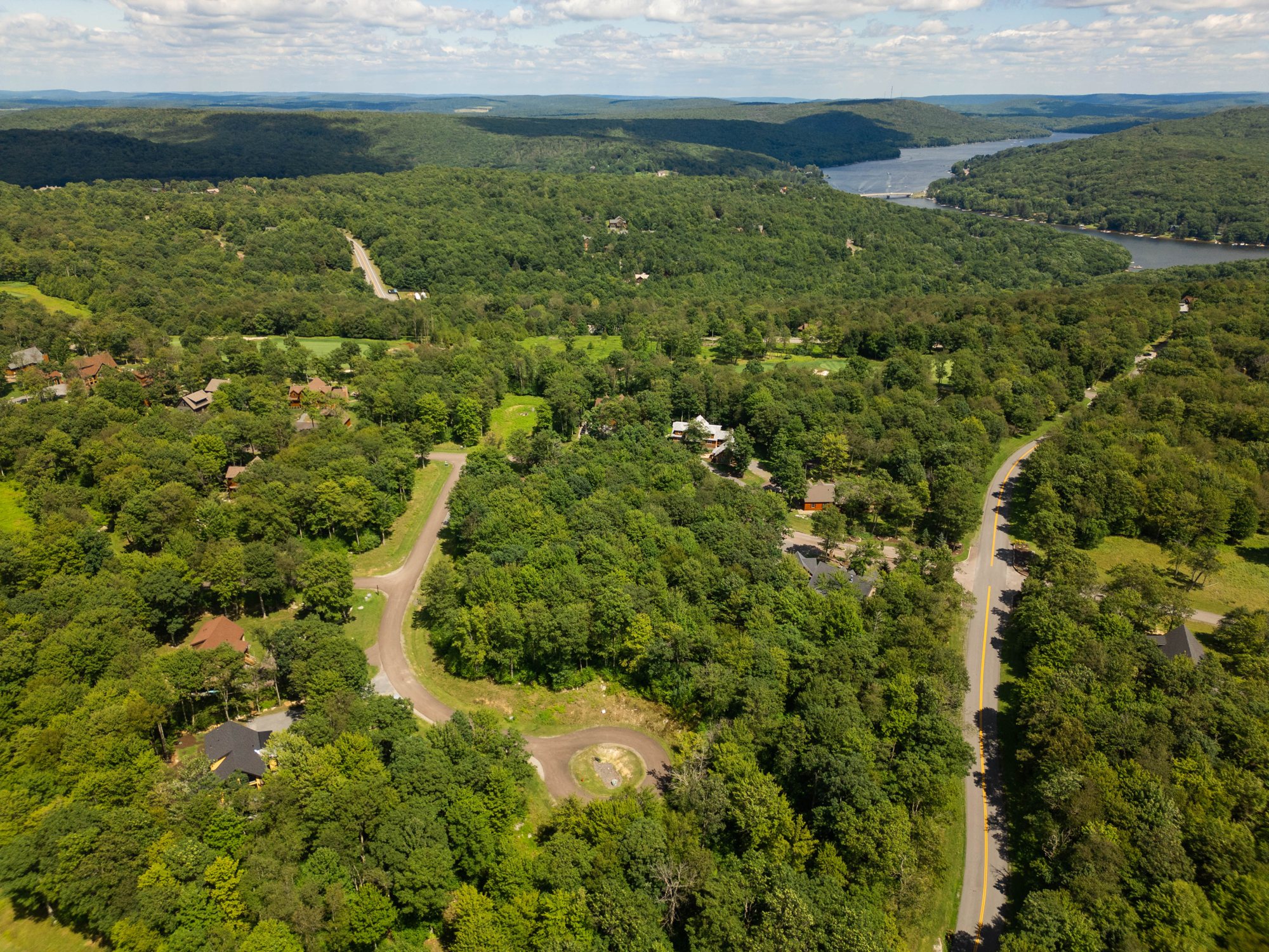 Aerial view over Marsh Mountain: the Eagle's Perch sits in the trees at lower left, the Lodestone golf course runs through the middle, and Deep Creek Lake is on the horizon at upper right
