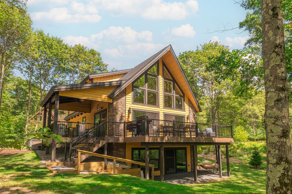 The Eagle's Perch from the yard — stacked stone, cedar siding, the wraparound deck and the gable window wall