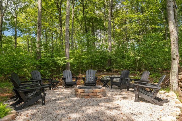 The stone fire pit ringed with Adirondack chairs, out in the trees