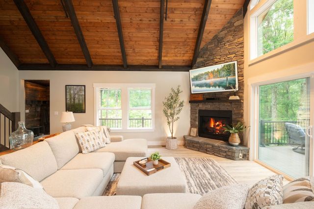 The great room wide open — cathedral ceilings, stacked-stone fireplace, and the 