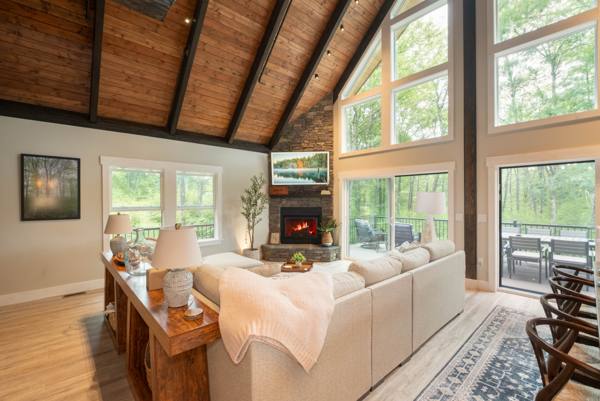 The great room under cathedral wood-plank ceilings and dark timber beams, with t