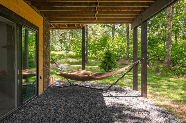A hammock in the shade under the deck, steps from the lower-level slider. The qu