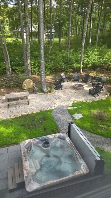 The hot tub with the jets running, the fire pit ring beyond it in the trees