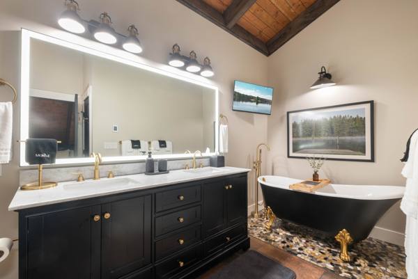 The en-suite: a black soaking clawfoot tub on river stone, marble counters, brus